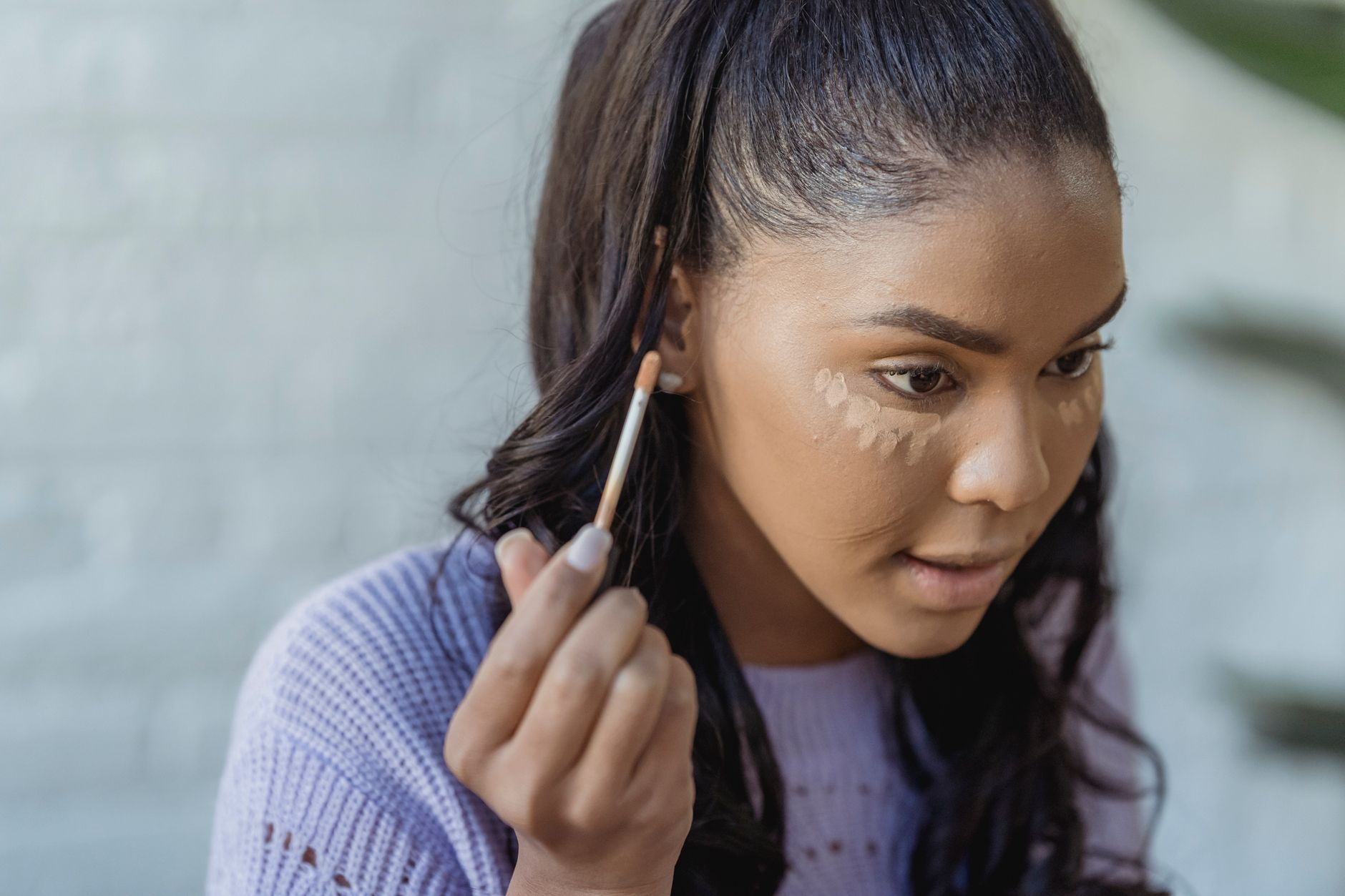 woman applying concealer under her eyes with a wand applicator