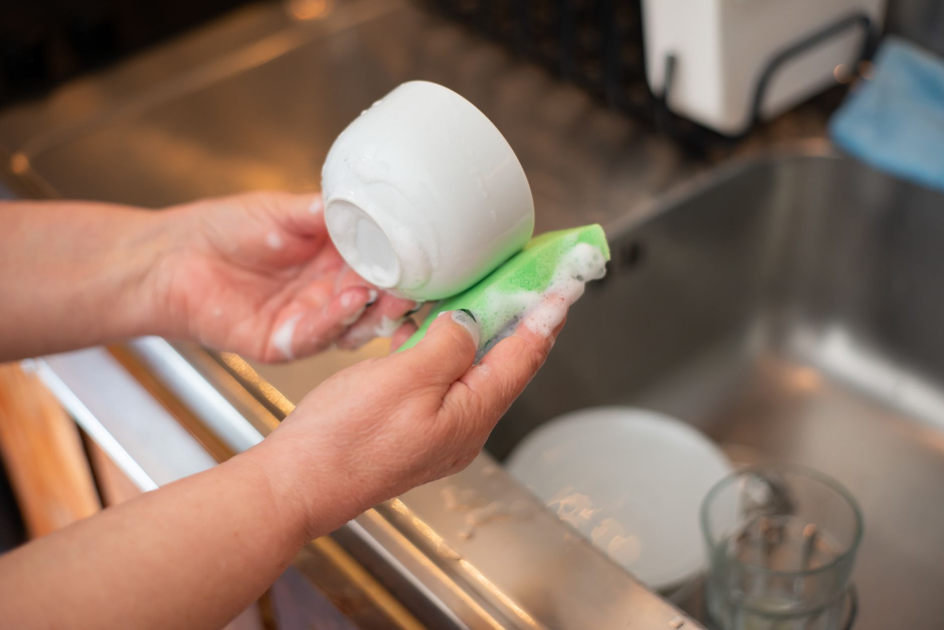 hands scrubbing a plate with soapy water and a sponge