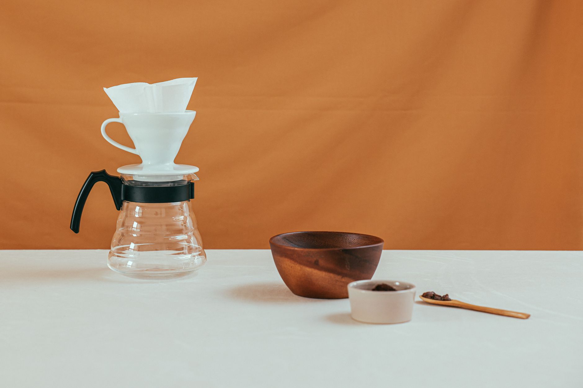 a glass pour over coffee carafe with a wooden collar on a table