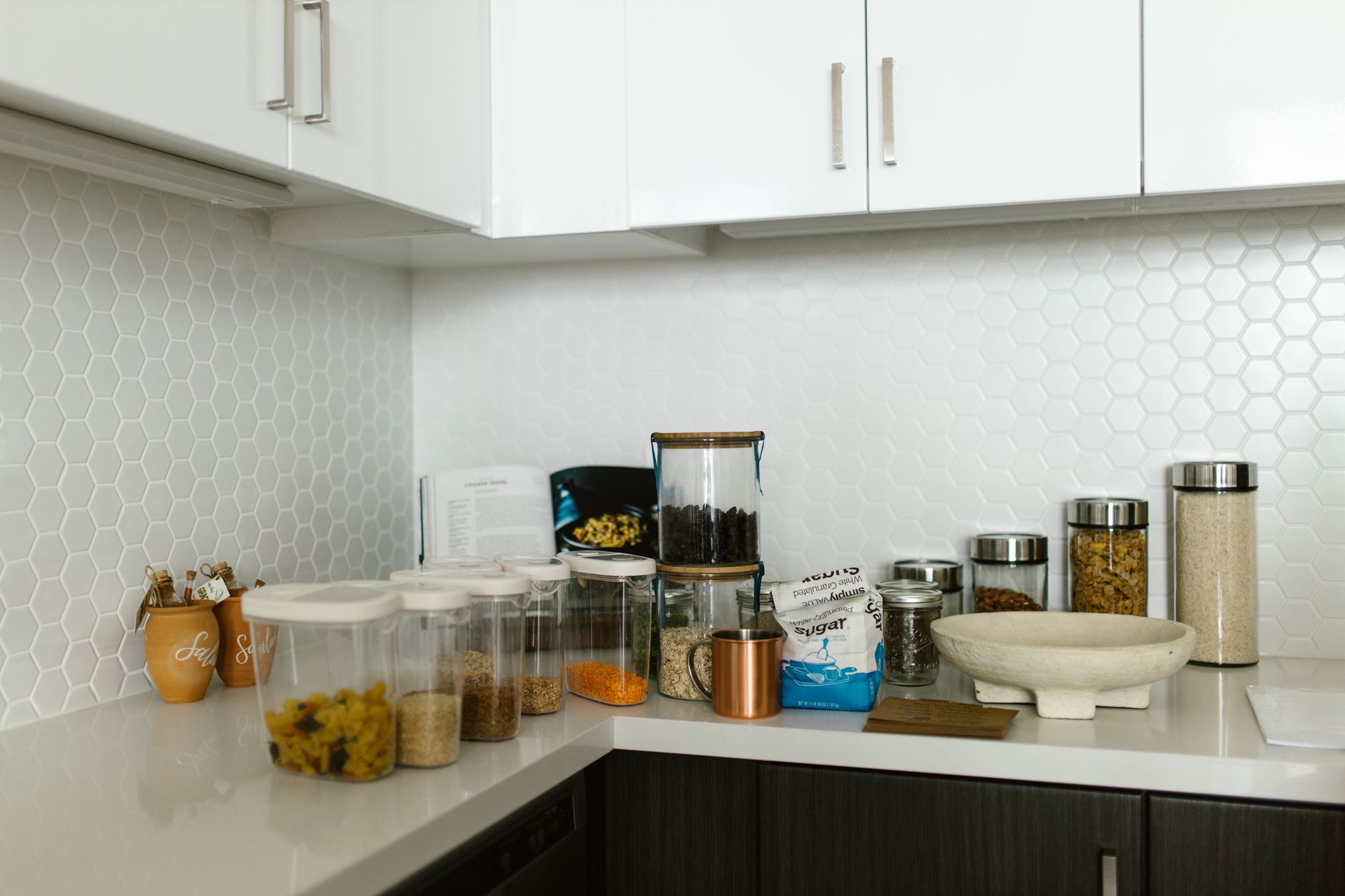 A set of glass food storage containers with plastic lids on a kitchen counter
